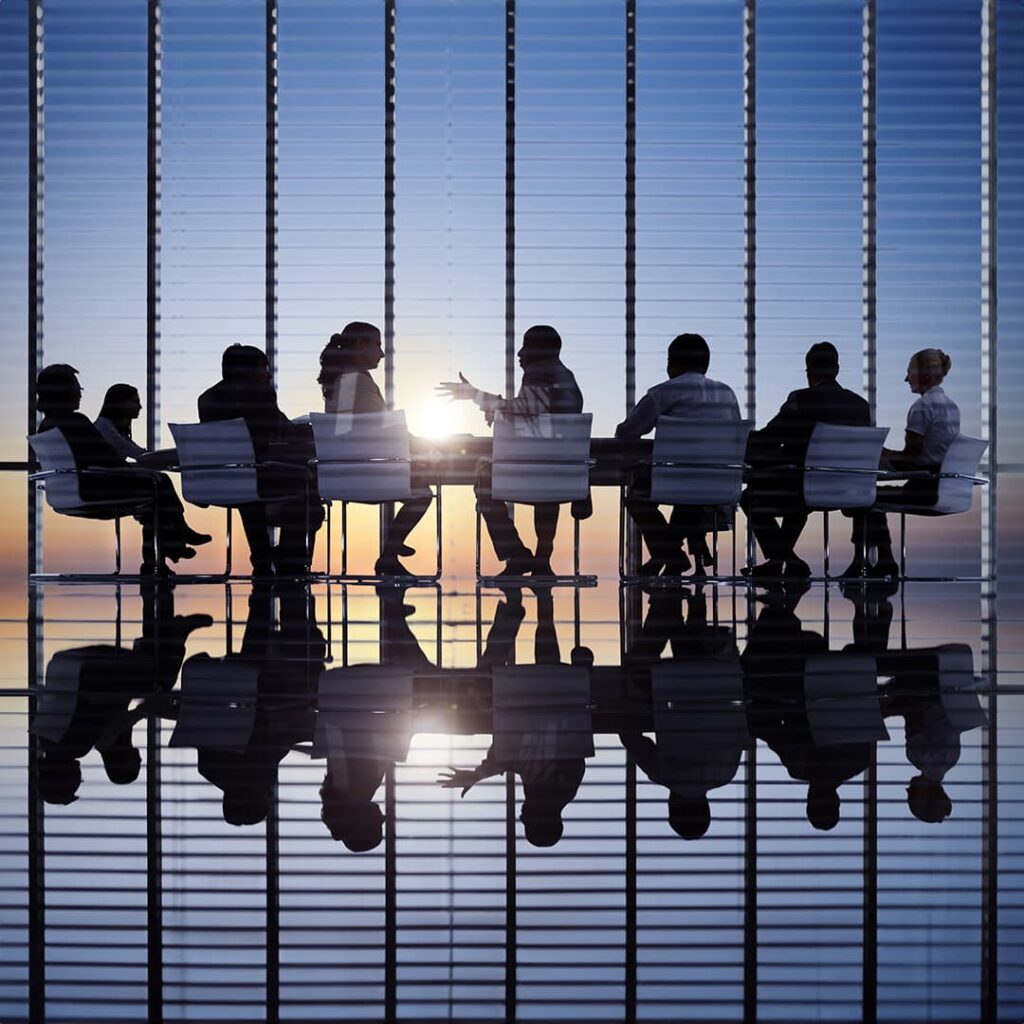 Agents silhouetted at conference table by sun