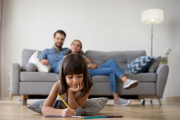 Couple on the couch watching their kid draw