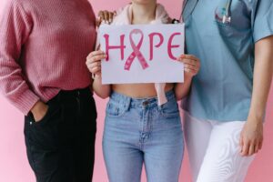 Three women with hope sign and breast cancer awareness ribbon