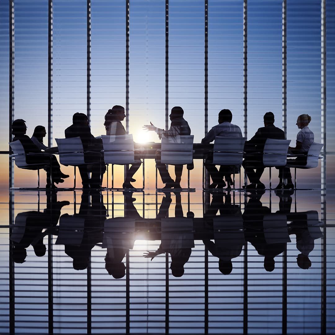 Agents silhouetted at conference table by sun